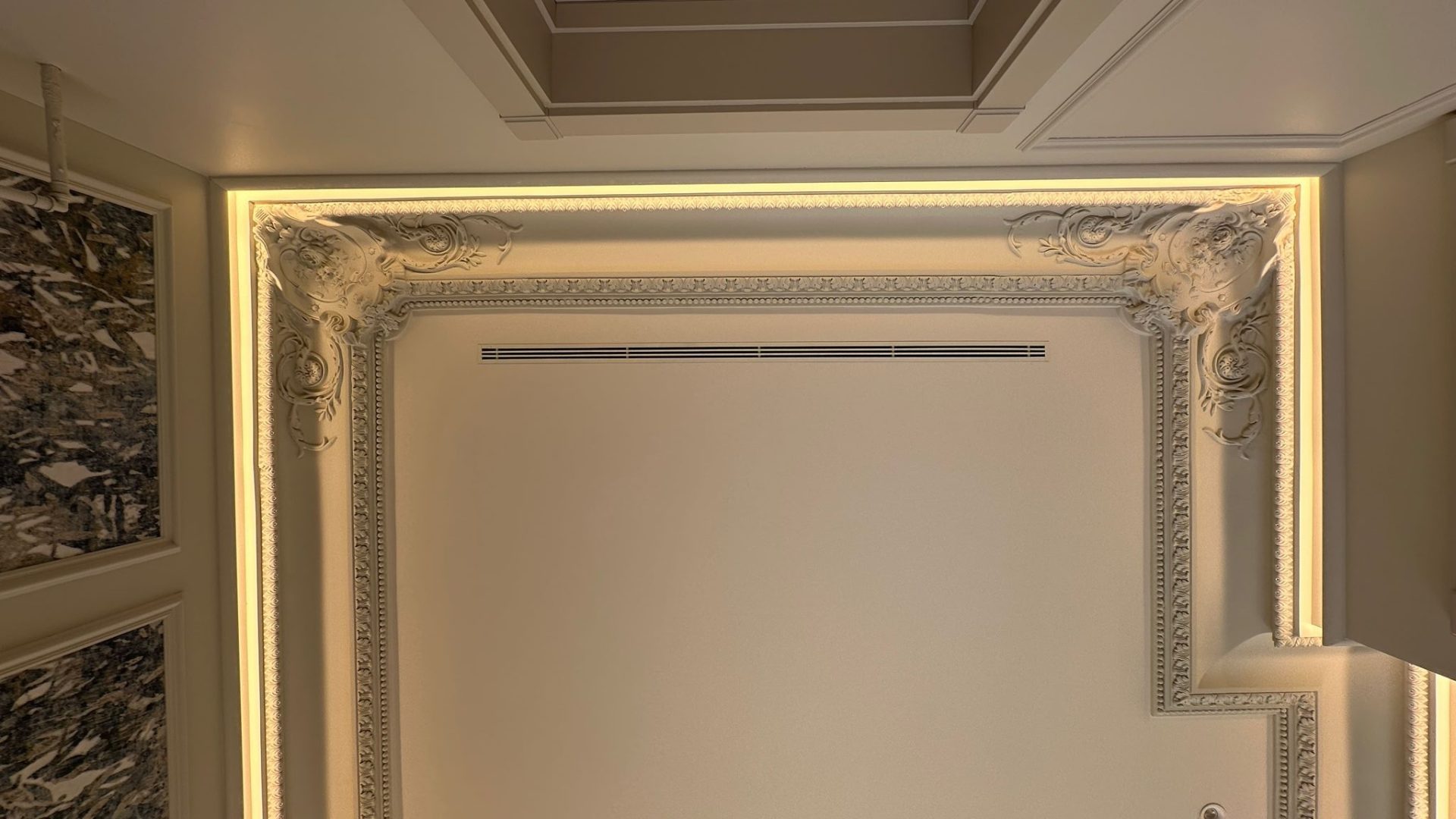 Integración de difusor de ranura para climatización invisible en techo foseado con iluminación LED y cornisas decorativas